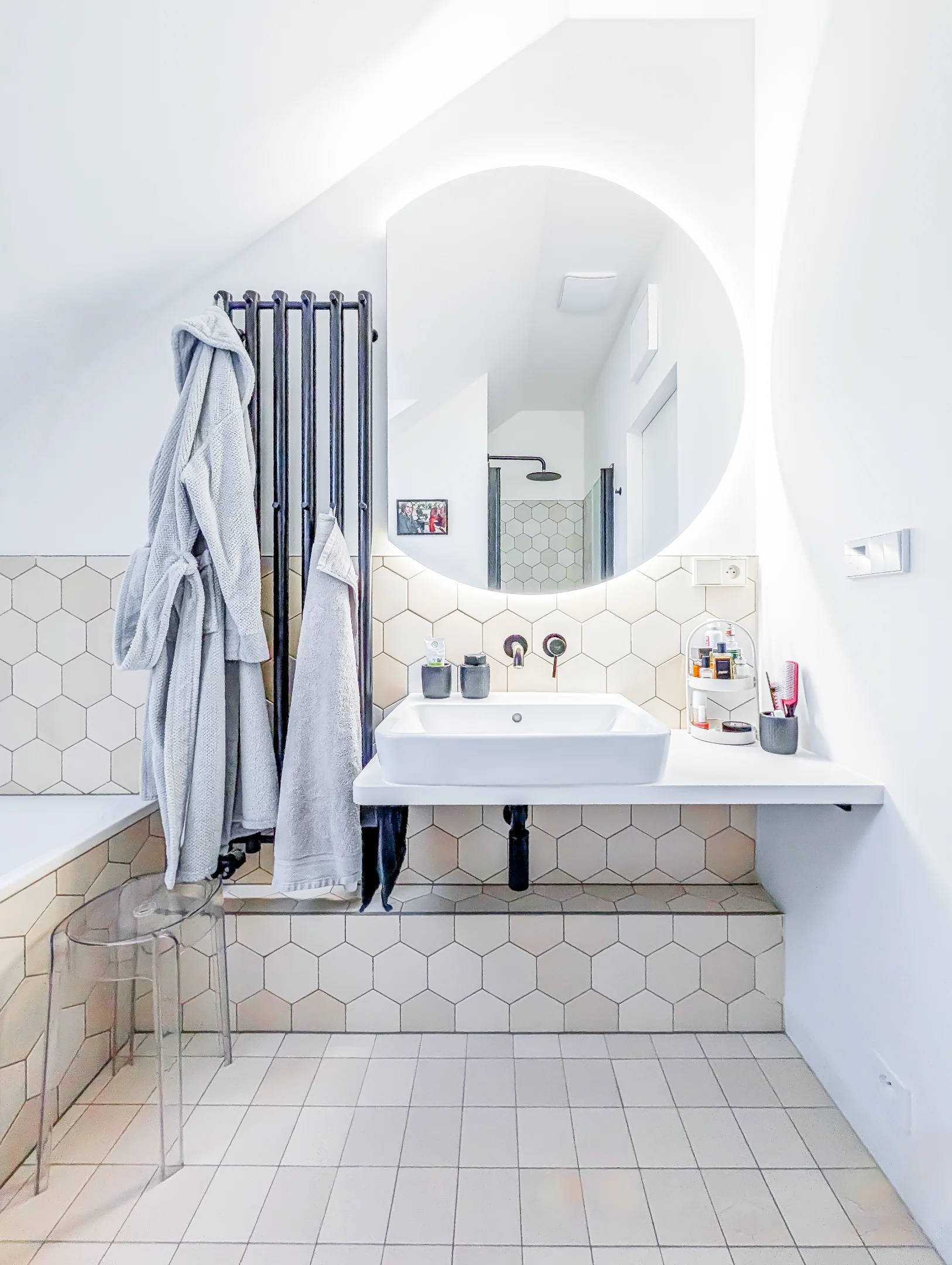 Moderní koupelna s umyvadlem zrcadlem a hexagonálními obklady.